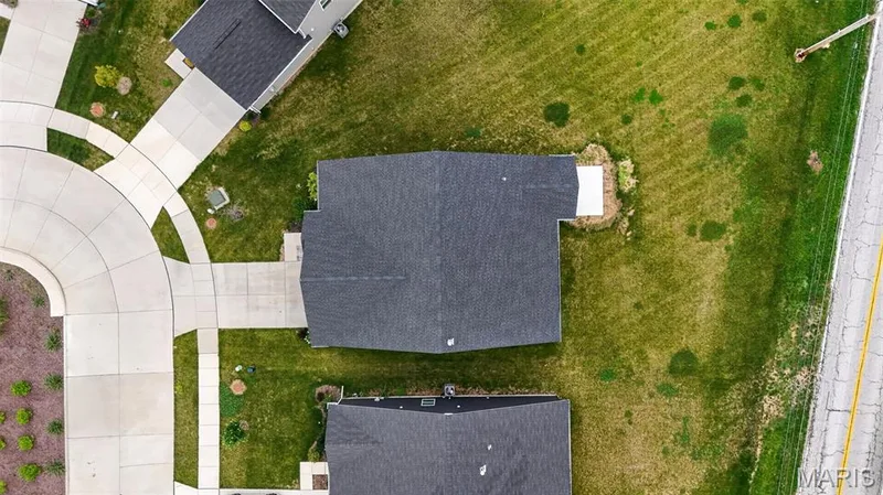 Property featuring a dark shingle roof, concrete driveway, and surrounding green lawn — 112 Creek Haven Court, Lake St. Louis, MO 63367