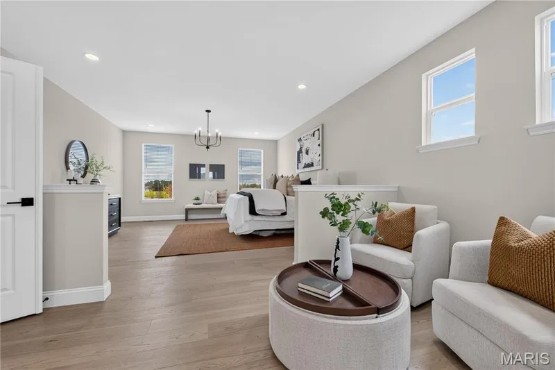Main floor Primary Bedroom featuring light wood-finish flooring throughout the expansive interior — 26 Valor Way, O'Fallon, MO 63385