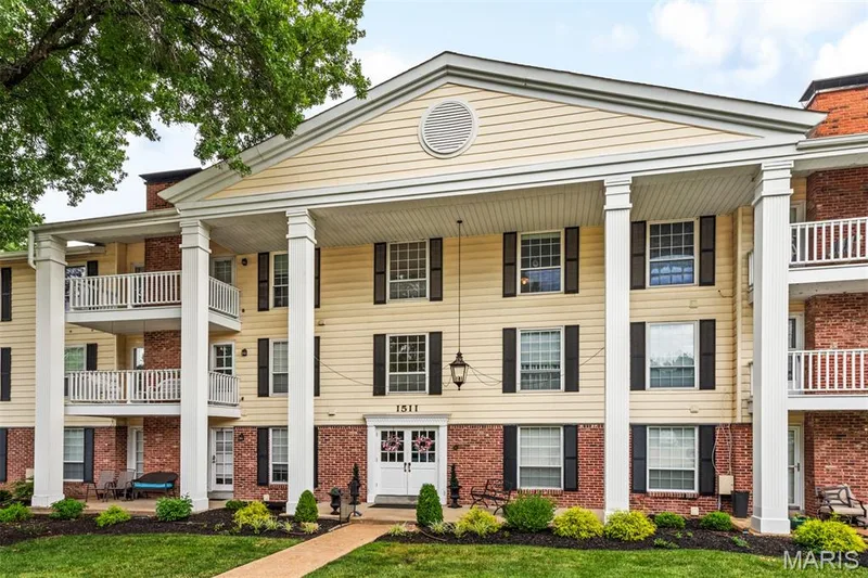 Multi-story building featuring a prominent portico with white columns, light-colored siding, and brick accents — 1511 Hampton Hall Drive #10, Chesterfield, MO 63017