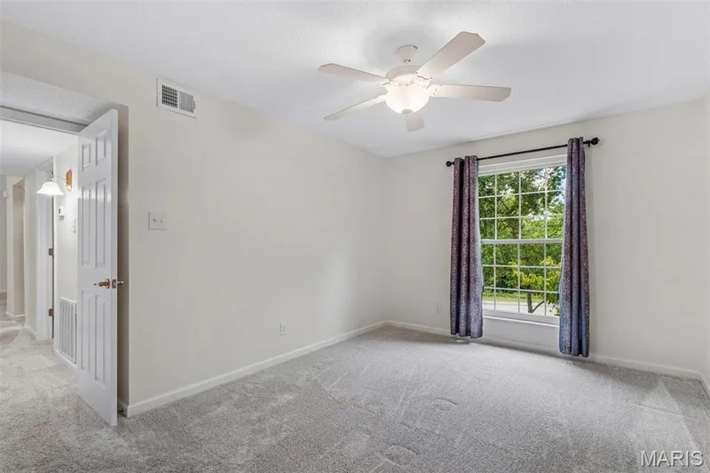 Neutral wall paint, ceiling fan with integrated lighting, window with a white grid, and plush carpet flooring — 1511 Hampton Hall Drive #10, Chesterfield, MO 63017