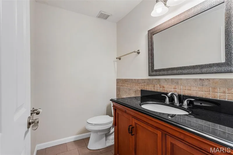 Wood-finish vanity with black countertop, undermount sink, and brushed nickel fixtures — 1511 Hampton Hall Drive #10, Chesterfield, MO 63017