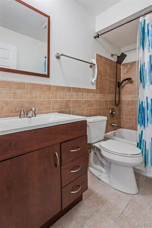 Dark wood-finish vanity with chrome hardware, white rectangular sink, tile flooring, and tiled shower surround with a rain shower head — 1511 Hampton Hall Drive #10, Chesterfield, MO 63017