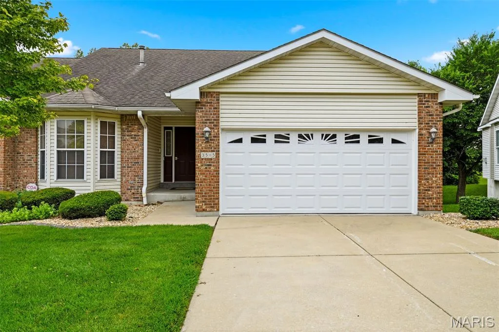 Brick and siding exterior featuring a prominent two-car garage with decorative window inserts — 3515 Truman Terrace Drive #65, St Charles, MO 63301
