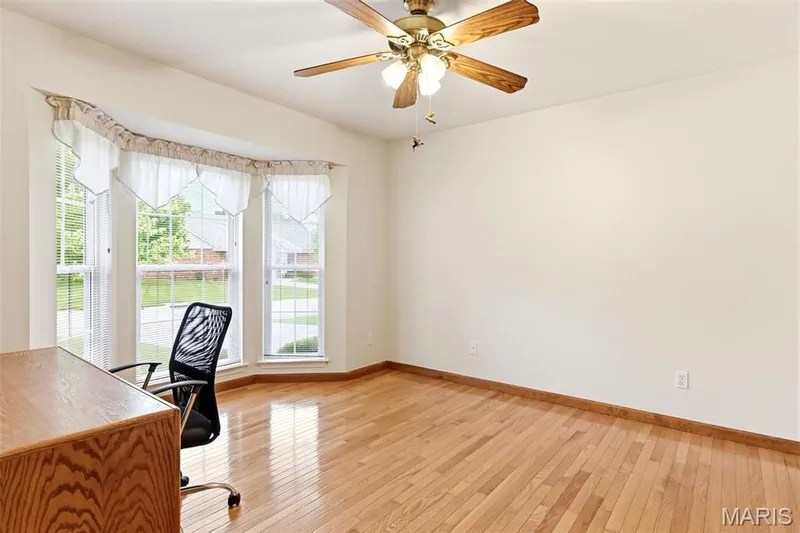 Bright room featuring a three-panel bay window, light wood-finish flooring, and a ceiling fan with integrated lighting — 3515 Truman Terrace Drive #65, St Charles, MO 63301