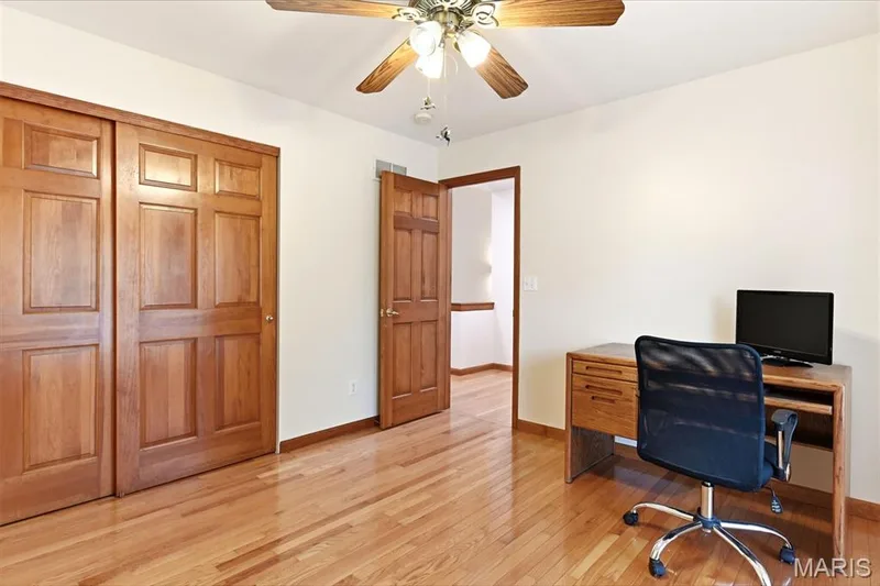 Room featuring wood-finish flooring throughout, two panel-style doors, and a ceiling fan with light fixture — 3515 Truman Terrace Drive #65, St Charles, MO 63301