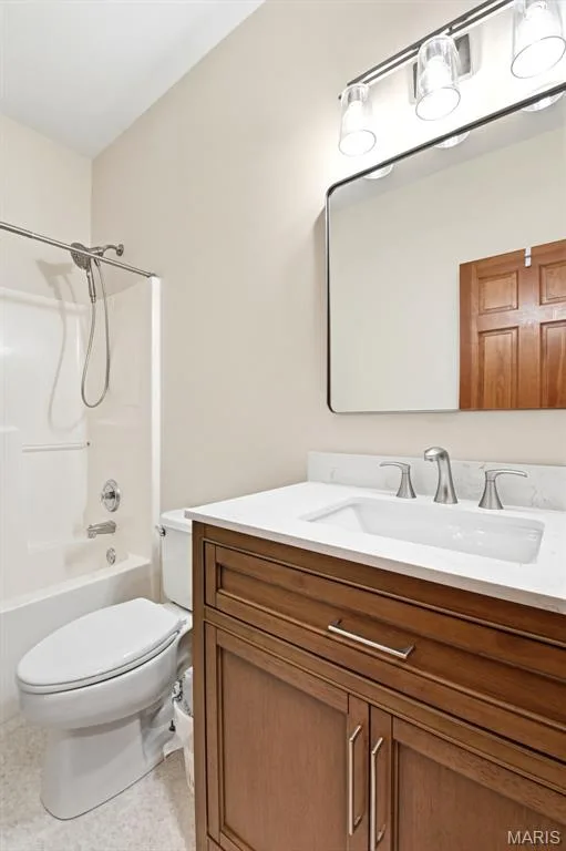 Bathroom featuring a wood-finish vanity with a white countertop and integrated sink, brushed nickel faucet, and a wall-mounted mirror — 3515 Truman Terrace Drive #65, St Charles, MO 63301