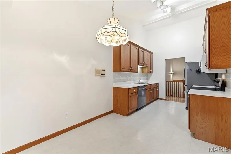 Kitchen with wood cabinetry, light-toned countertops, and a tile backsplash — 3515 Truman Terrace Drive #65, St Charles, MO 63301