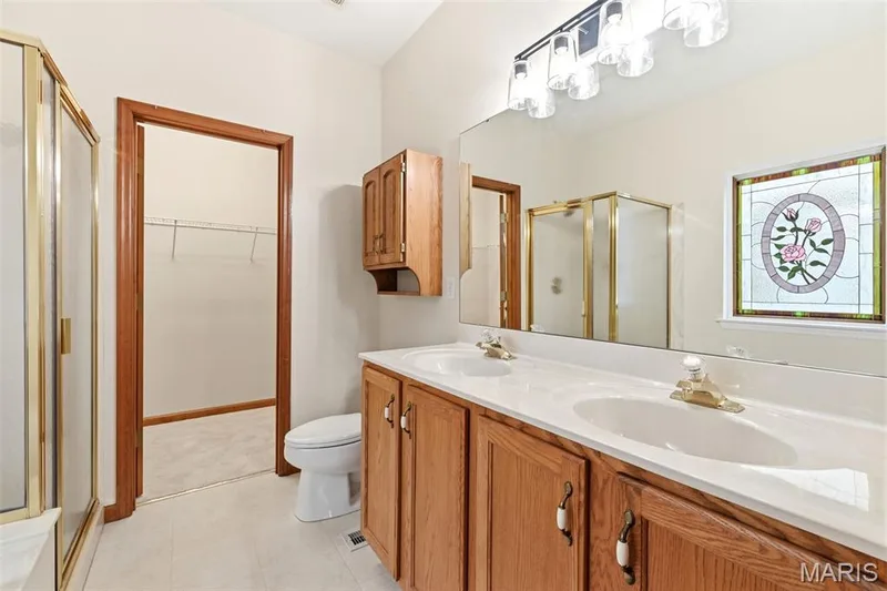 Bathroom featuring a double vanity with wood cabinetry and an integrated countertop — 3515 Truman Terrace Drive #65, St Charles, MO 63301