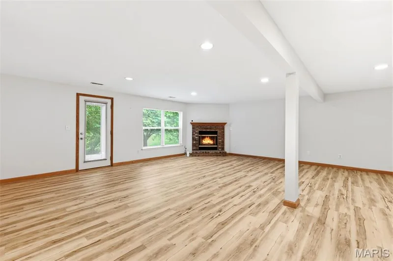 Spacious room featuring wood-finish flooring, recessed lighting, and a brick fireplace with a wood mantle — 3515 Truman Terrace Drive #65, St Charles, MO 63301