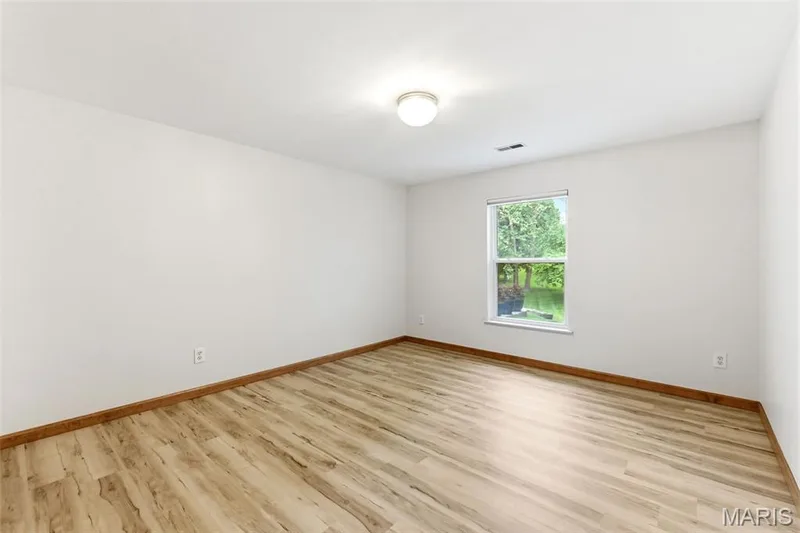 Room featuring wood-finish flooring, white walls, and a recessed window with an exterior tree-lined view — 3515 Truman Terrace Drive #65, St Charles, MO 63301