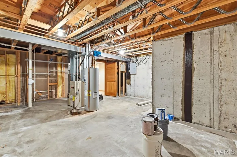 Unfinished basement featuring exposed wood joists, concrete flooring, concrete block walls, and a utility area with water heater and furnace — 3515 Truman Terrace Drive #65, St Charles, MO 63301