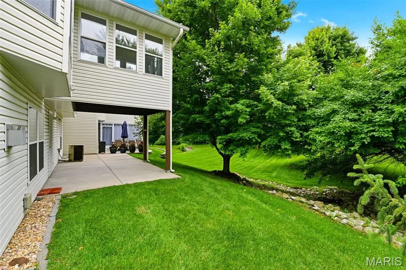 Expansive green lawn featuring mature trees and a rock-lined drainage area — 3515 Truman Terrace Drive #65, St Charles, MO 63301