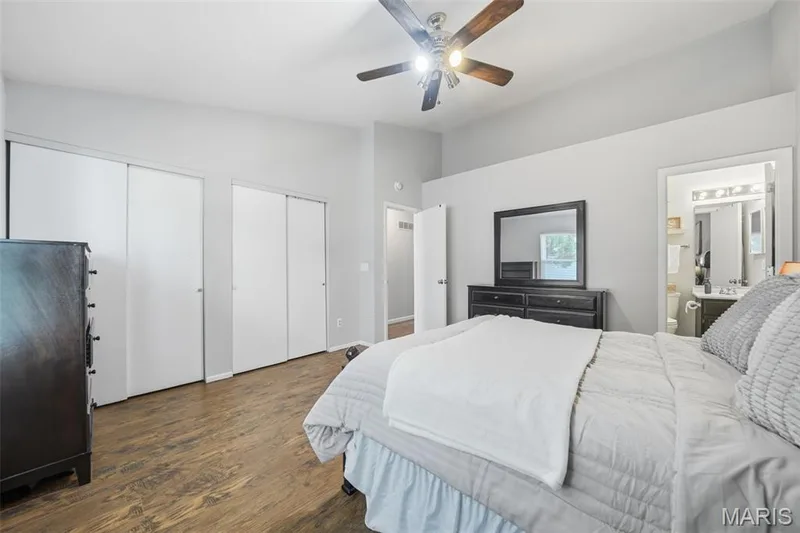 Bedroom featuring vaulted ceilings, wood-finish flooring, a ceiling fan with integrated lighting, and multiple sliding closet doors — 2510 Balaji Court, Wildwood, MO 63011