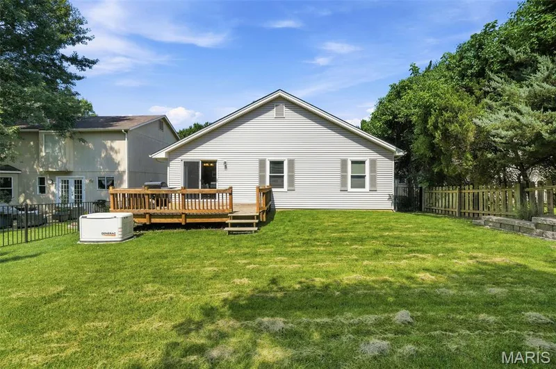 Expansive green lawn with a wooden deck featuring railings and steps — 2510 Balaji Court, Wildwood, MO 63011