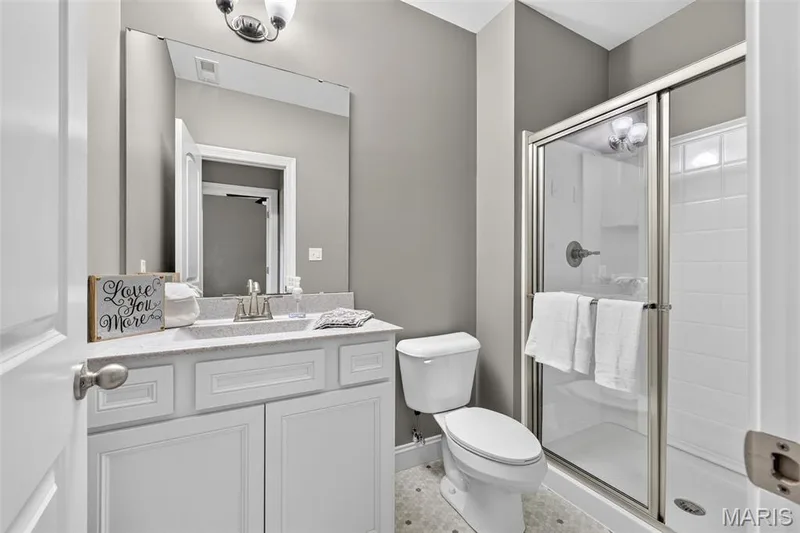 White vanity with shaker-style cabinetry, a speckled countertop, and an undermount sink — 401 Hamlet Court, O'Fallon, MO 63367