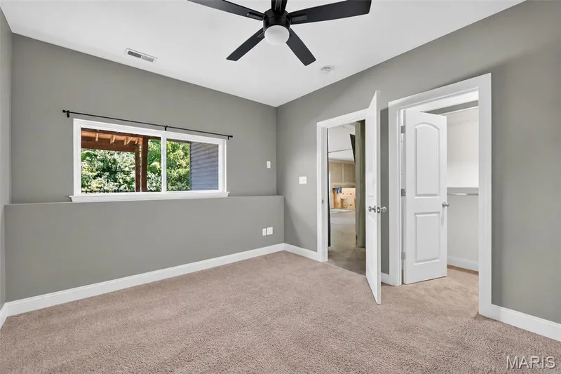 Carpeted flooring, neutral wall color, ceiling fan, white trim, and a window with exterior views — 401 Hamlet Court, O'Fallon, MO 63367