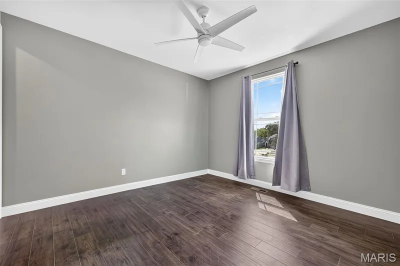 Wood-finish flooring with white trim, a window with white casing, and a ceiling fan — 401 Hamlet Court, O'Fallon, MO 63367