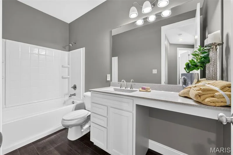White vanity with integrated sink, light-toned countertop, and dark wood-finish flooring — 401 Hamlet Court, O'Fallon, MO 63367