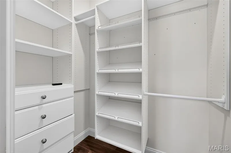 Custom closet system featuring multiple adjustable shelves, integrated drawer storage with brushed nickel hardware, and dedicated hanging rods — 401 Hamlet Court, O'Fallon, MO 63367