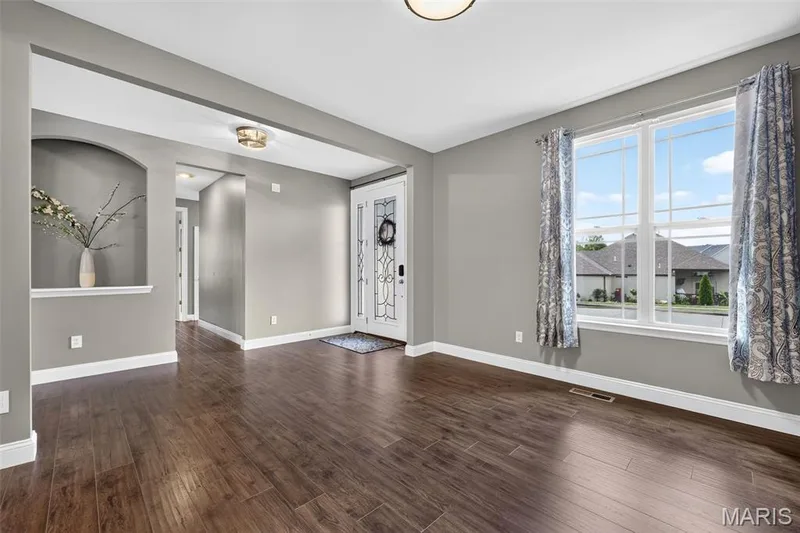 Wood-finish flooring throughout, framed window, decorative arched wall niche, recessed entryway, and a decorative front door with opaque glass — 401 Hamlet Court, O'Fallon, MO 63367