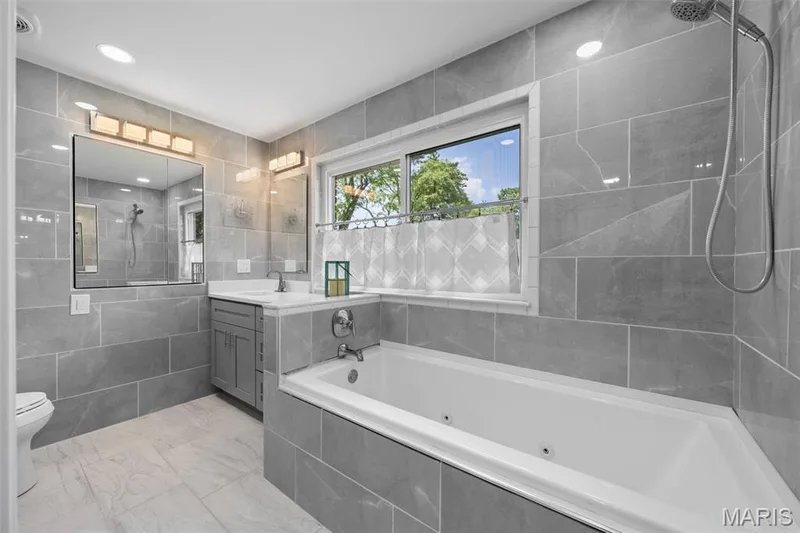 Completely updated hall bathroom features a jacuzzi tub, floor to ceiling marble and a large window — 312 Diplomat Lane, Chesterfield, MO 63017