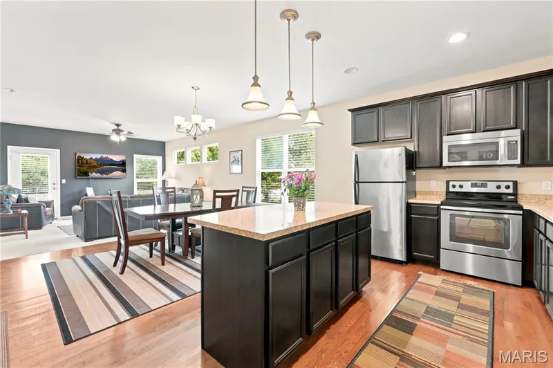 Kitchen featuring dark wood cabinetry, stainless steel appliances, and a central island with a light-toned countertop — 226 City Gate Lane, St Charles, MO 63303