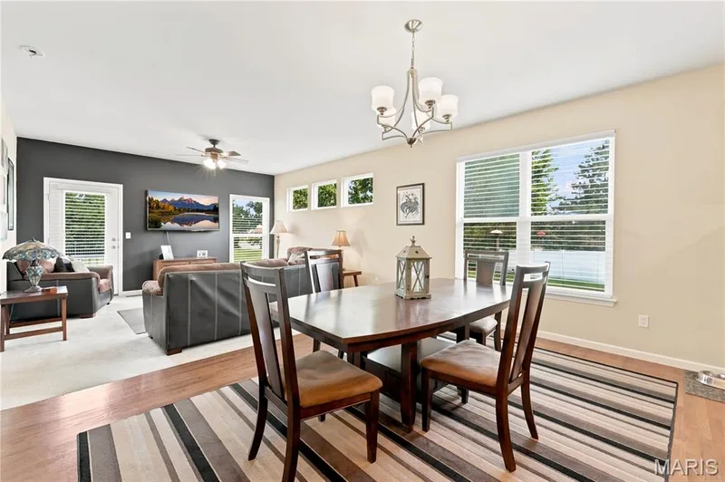 Open-concept living dining area featuring wood-finish flooring, recessed lighting, and ample natural light from multiple windows — 226 City Gate Lane, St Charles, MO 63303