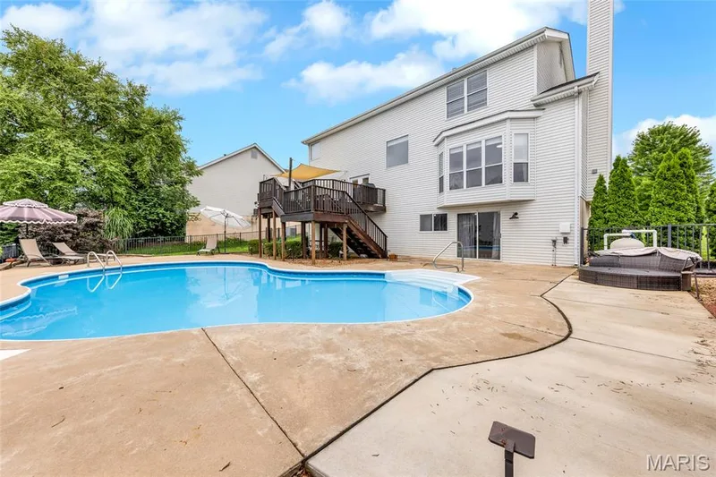 Vacation vibes just outside your door. A spacious kidney-shaped saltwater pool and vast concrete patio sit perfectly positioned off the walk-out family room. — 501 Oxborough Court, Cottleville, MO 63376