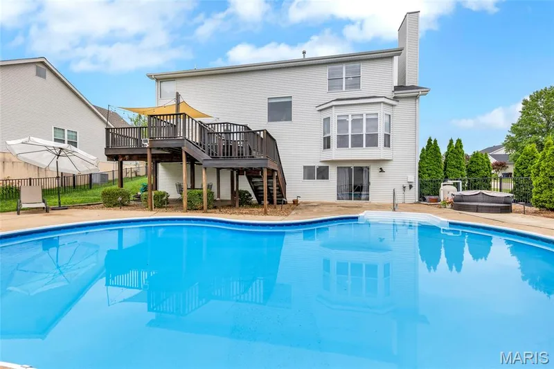 A spectacular, resort-worthy retreat. This spacious, kidney-shaped saltwater pool boasts a versatile shallow-to-deep design and a vast concrete deck engineered for elite outdoor entertainment. — 501 Oxborough Court, Cottleville, MO 63376