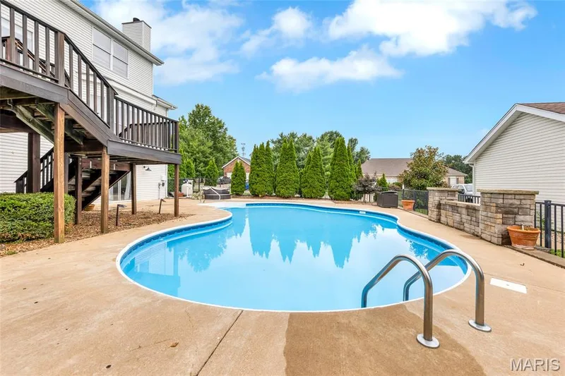 Curved in-ground swimming pool with concrete surround — 501 Oxborough Court, Cottleville, MO 63376