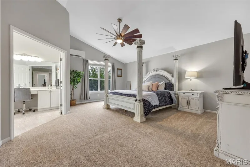 Spacious bedroom featuring vaulted ceilings, light tan carpeting, and a built-in ceiling fan with integrated lighting — 501 Oxborough Court, Cottleville, MO 63376