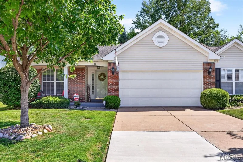 Single-story residence featuring a brick and siding exterior, an attached two-car garage, mature landscaping, a concrete driveway, and a covered front entry — 30 Hunting Manor Drive, St Charles, MO 63303