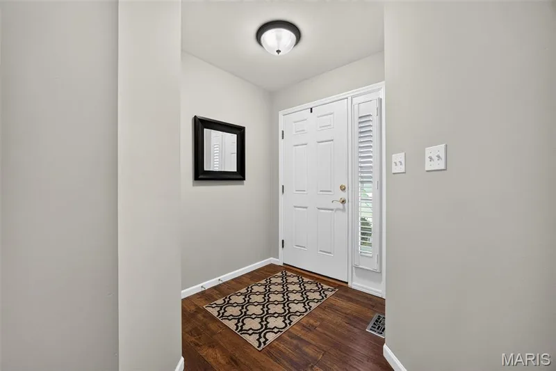 Entryway featuring wood-finish flooring, a white paneled entry door with a gold-tone handle, a coordinating sidelight with plantation shutters, and a semi-flush mount ceiling light — 30 Hunting Manor Drive, St Charles, MO 63303