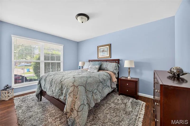 Spacious room with wood-finish flooring, light blue wall paint, and a large window with white blinds — 30 Hunting Manor Drive, St Charles, MO 63303