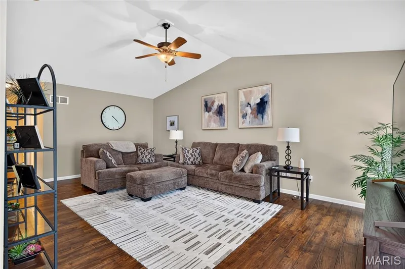 Spacious living area featuring vaulted ceilings, wood-finish flooring, a ceiling fan with integrated lighting, and neutral wall tones — 30 Hunting Manor Drive, St Charles, MO 63303