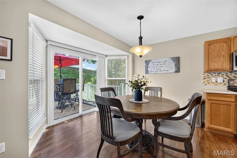 Dining area featuring wood-finish flooring, a bay window, and sliding glass doors opening to an outdoor deck — 30 Hunting Manor Drive, St Charles, MO 63303