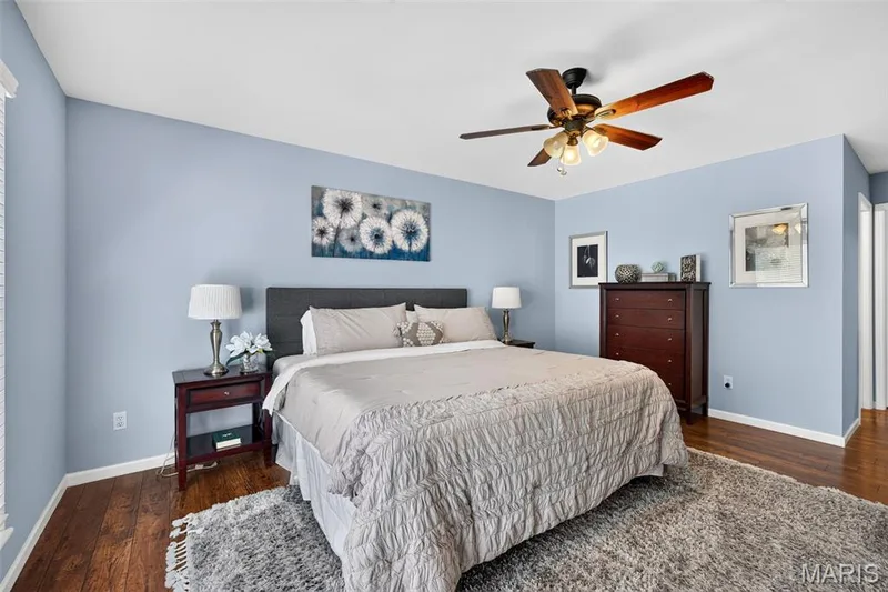 Bedroom featuring wood-finish flooring, light blue walls, and a ceiling fan with integrated lighting — 30 Hunting Manor Drive, St Charles, MO 63303