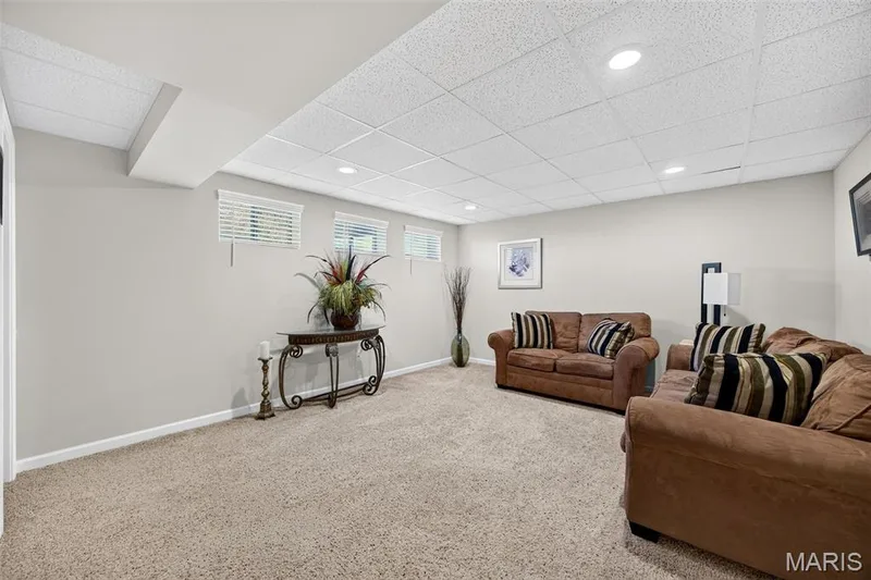 Carpeted lower level featuring a drop ceiling with recessed lighting, light gray walls, and three horizontal windows — 30 Hunting Manor Drive, St Charles, MO 63303