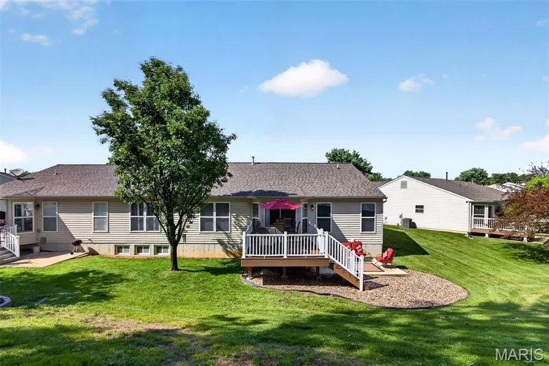 Rear exterior featuring a multi-level composite deck with white railings, a patio with gravel landscaping, and a sloped lawn — 30 Hunting Manor Drive, St Charles, MO 63303