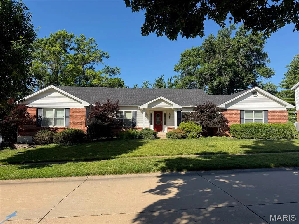 Brick and siding facade with a dark shingle roof, featuring a red entry door and a manicured lawn — 14238 Kinderhook Drive, Chesterfield, MO 63017