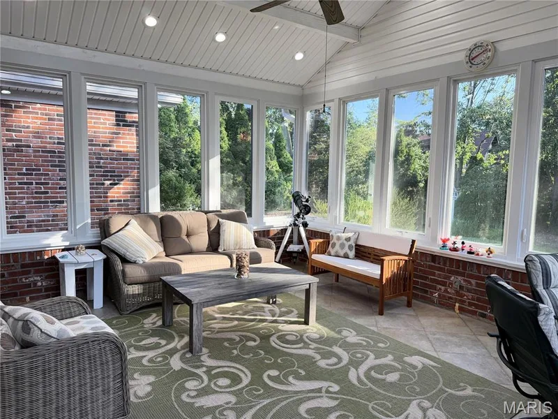 Sunroom featuring a vaulted ceiling with recessed lighting, ceiling fan, and extensive windows, brick knee walls, and tiled flooring — 14238 Kinderhook Drive, Chesterfield, MO 63017