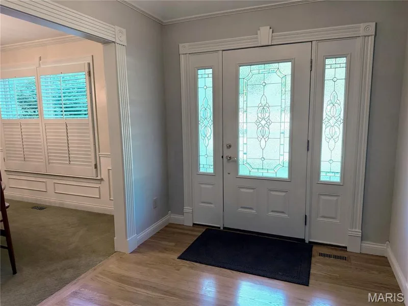 Entryway featuring decorative door trim, a transom window, sidelight windows with decorative glass, and wood-finish flooring — 14238 Kinderhook Drive, Chesterfield, MO 63017