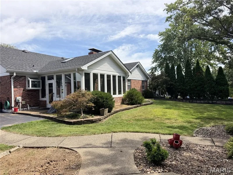 Brick exterior construction with an attached sunroom, mature landscaping, and a concrete pathway — 14238 Kinderhook Drive, Chesterfield, MO 63017