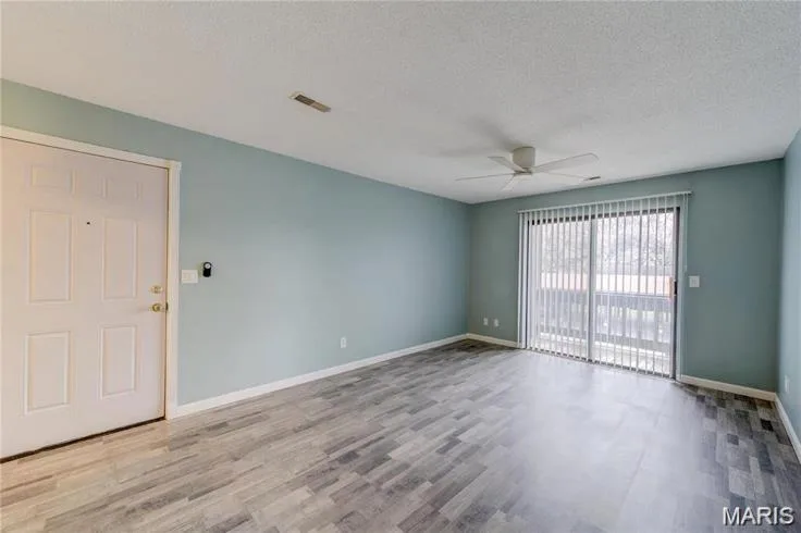 Living area featuring wood-finish flooring, a ceiling fan, and a light blue wall finish — 1430 Summergate Parkway #J, St Charles, MO 63303