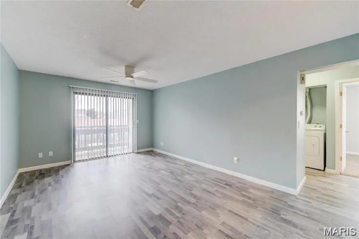 Spacious room featuring wood-finish flooring, light blue walls, and a ceiling fan — 1430 Summergate Parkway #J, St Charles, MO 63303