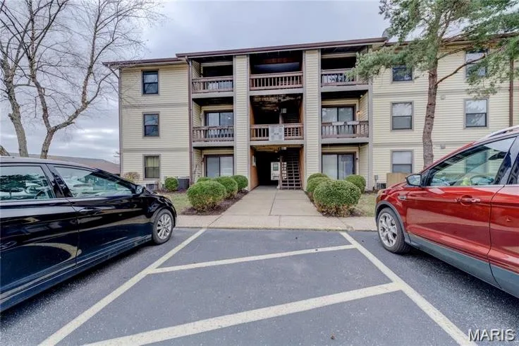 Three-story multi-unit building featuring horizontal siding, multiple balconies with wood railings, and individual sliding glass doors — 1430 Summergate Parkway #J, St Charles, MO 63303