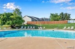 Community swimming pool featuring a concrete deck and multiple lounge chairs — 1430 Summergate Parkway #J, St Charles, MO 63303