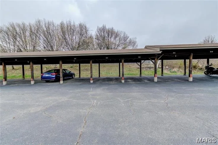 Covered parking structure featuring multiple bays, a composite roof, and wood support beams with concrete bases — 1430 Summergate Parkway #J, St Charles, MO 63303