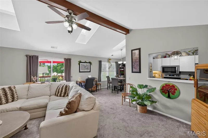 Spacious living area featuring vaulted ceilings with exposed wood beams, skylights, and a ceiling fan — 974 Windstream Drive #38, St Peters, MO 63376
