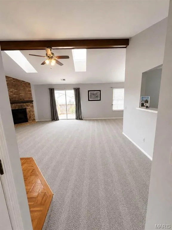 Vaulted ceilings with skylights, wood-finish beam, brick fireplace, ceiling fan, and sliding glass door — 974 Windstream Drive #38, St Peters, MO 63376